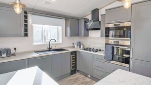 Una cocina moderna con gabinetes grises, estufa a gas, horno y dos lámparas colgantes.