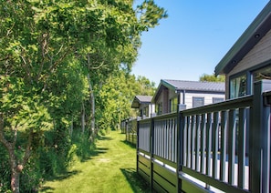 A row of cabins with a wooden fence, surrounded by trees and a clear sky. - 1 bedroom accommodation in Fowey (Fowey)