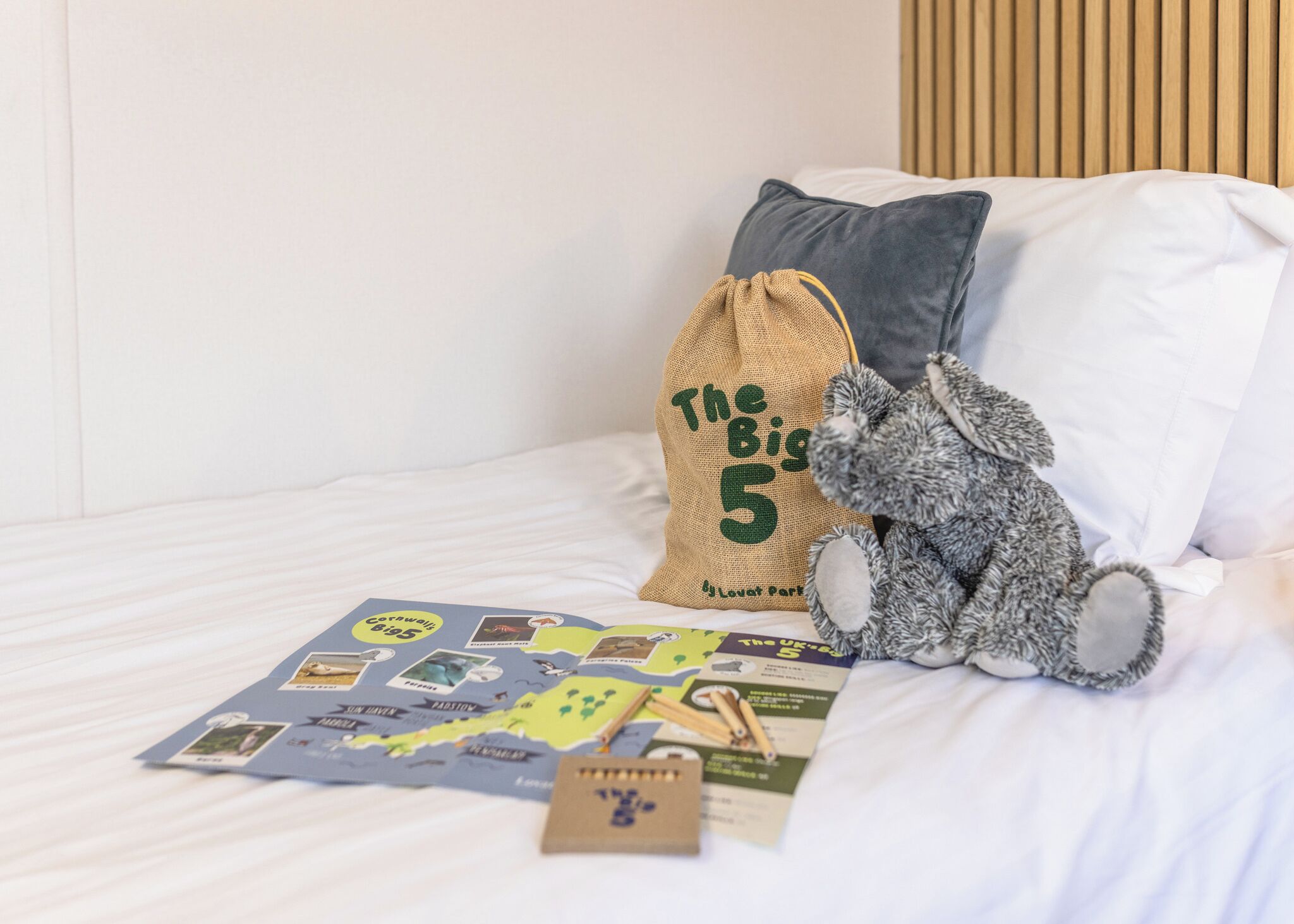 A bed with a pillow, a stuffed toy, and a board game.