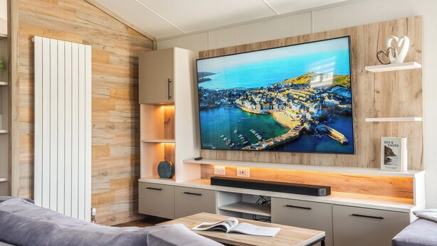 Una sala de estar moderna con un televisor de pantalla plana grande, paneles de madera, un sofá y una mesa de centro.