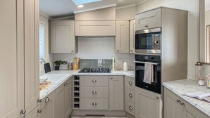 Et kompakt køkken med ovenlys, indbygget ovn og moderne skabe.
