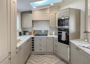 A compact kitchen with a skylight, built-in oven, and modern cabinetry. - 1 bedroom accommodation in Fowey (Fowey)