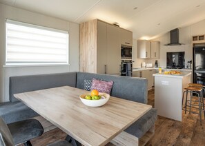 Cocina moderna con una isla central, electrodomésticos integrados y un área de descanso con mesa y cojines.