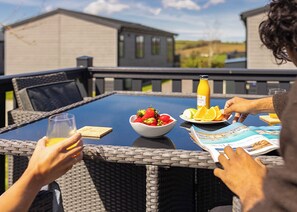 Una mesa de comedor con un cuenco de fruta, una botella de jugo y una revista.