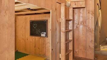 Una habitación de madera con un muro de pizarra, un estante pequeño y un tapete en el suelo.