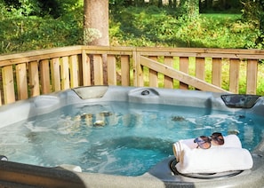 A hot tub with a wooden deck, surrounded by greenery. - Safari Tent sleeps 6 (Hayle)