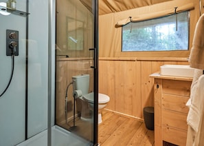 A compact bathroom with a glass shower enclosure, a toilet, and a wooden vanity with a sink. - Safari Tent sleeps 6 (Hayle)