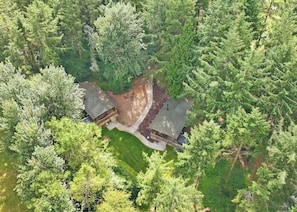 An aerial view of a cabin surrounded by dense forest, with a clear path leading to the entrance. - Safari Tent sleeps 6 (Hayle)