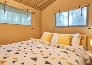 A bedroom with a bed, two windows, and a lamp. - Safari Tent sleeps 6 (Hayle)