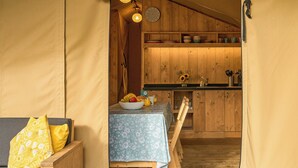 A tented accommodation with a dining area, wooden cabinets, and a clock on the wall. - Safari Tent sleeps 6 Pet Friendly (Hayle)