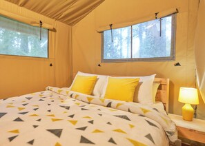A bed with a geometric-patterned bedspread, two windows with curtains, and a bedside lamp. - Safari Tent sleeps 6 Pet Friendly (Hayle)