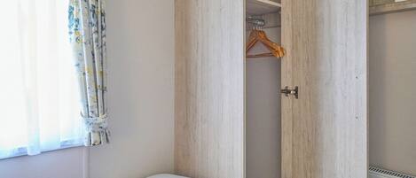 A bedroom with a bed, a wardrobe, and a window with curtains.