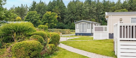 A caravan park with neatly trimmed hedges, a gravel path, and mobile homes.