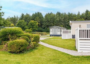 A caravan park with neatly trimmed hedges, a gravel path, and mobile homes. - Standard 3 Bedroom sleeps 8 (Hayle)
