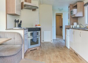 A compact kitchen with a built-in oven, a microwave, and a sink. - Standard 2 Bedroom sleeps 6 Pet Friendly (Hayle)