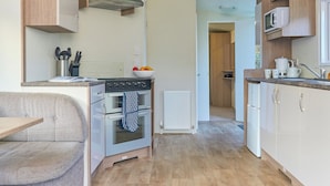 A compact kitchen with a built-in oven, a microwave, and a sink. - Standard 2 Bedroom sleeps 6 Pet Friendly (Hayle)