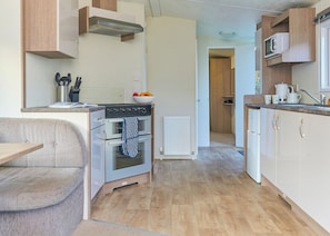 A compact kitchen with a built-in oven, a microwave, and a sink. - Standard 2 Bedroom sleeps 6 Pet Friendly (Hayle)