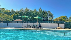 A swimming pool with clear blue water, surrounded by a fence, and shaded by two umbrellas. - Standard 2 Bedroom sleeps 6 Pet Friendly (Hayle)