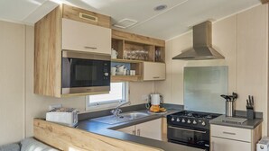 Uma cozinha compacta com micro-ondas, fogão, pia e armários de madeira.