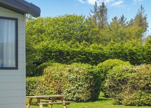A house with a visible window and a wooden picnic table in the foreground. - Superior 2 Bedroom sleeps 6 (Hayle)