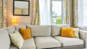 Un salon avec un canapé, une lampe et une fenêtre avec des rideaux.