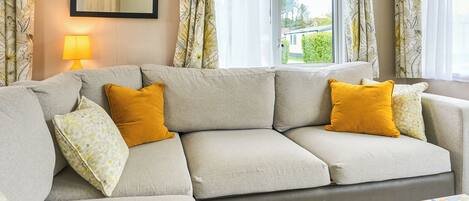 A living room with a sofa, a lamp, and a window with curtains.