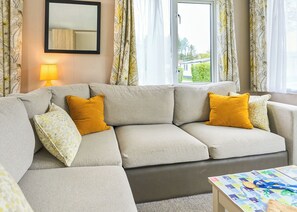 A living room with a sofa, a lamp, and a window with curtains.