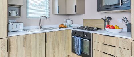 A modern kitchen with a built-in toaster, a sink, a stove, and a microwave.