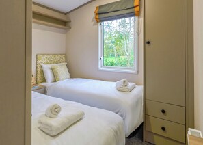 A bedroom with two beds, a window with a view of trees, and a wardrobe. - Superior 2 Bedroom sleeps 6 Pet Friendly (Hayle)