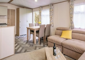 A compact living space with a sofa, dining table, chairs, and a kitchen area. - Superior 3 Bedroom sleeps 8 Pet Friendly (Hayle)