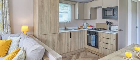 A compact kitchenette with a microwave, oven, and sink.