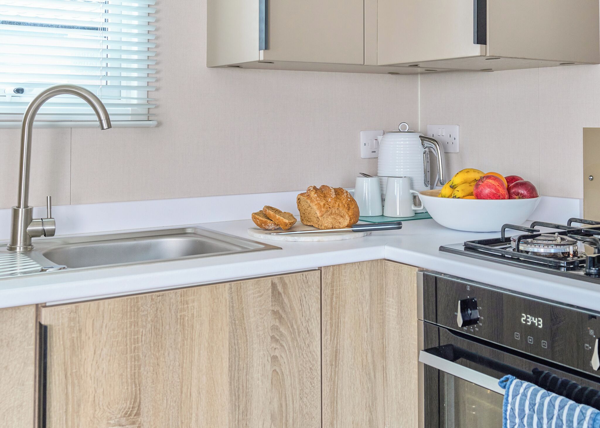 A modern kitchen with a sink, stove, and a bowl of fruit.