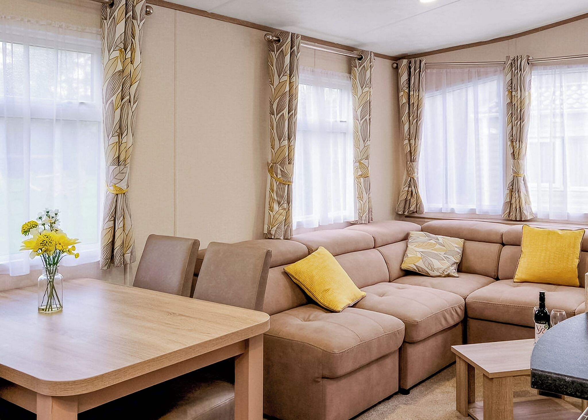 A living room with a sectional sofa, a wooden coffee table, and a vase with flowers.