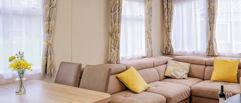 A living room with a sectional sofa, a wooden coffee table, and a vase with flowers.