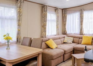 A living room with a sectional sofa, a wooden coffee table, and a vase with flowers. - Superior 3 Bed (Pet) (Hayle)