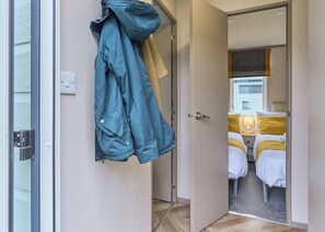 A hotel room with a bed, a nightstand, and a door leading to another room. - Superior 3 Bedroom sleeps 8 Pet Friendly (Hayle)