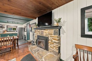 A cozy interior with a stone fireplace, wooden ceiling, and a dining area. - Cabin Near Stratton and Mt. Snow w/hot tub, sauna (Wardsboro)