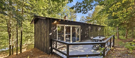 A cabin with a deck, surrounded by trees.
