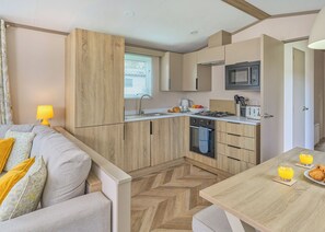 Een kleine keuken met houten kastjes, een magnetron en een gasfornuis.