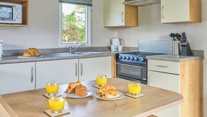 A modern kitchen with a dining table set for breakfast, including croissants and orange juice.
