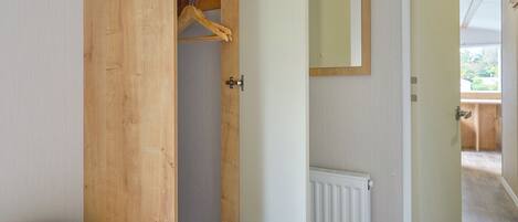 A bedroom with a wooden wardrobe, a bed, a radiator, and a mirror on the wall.