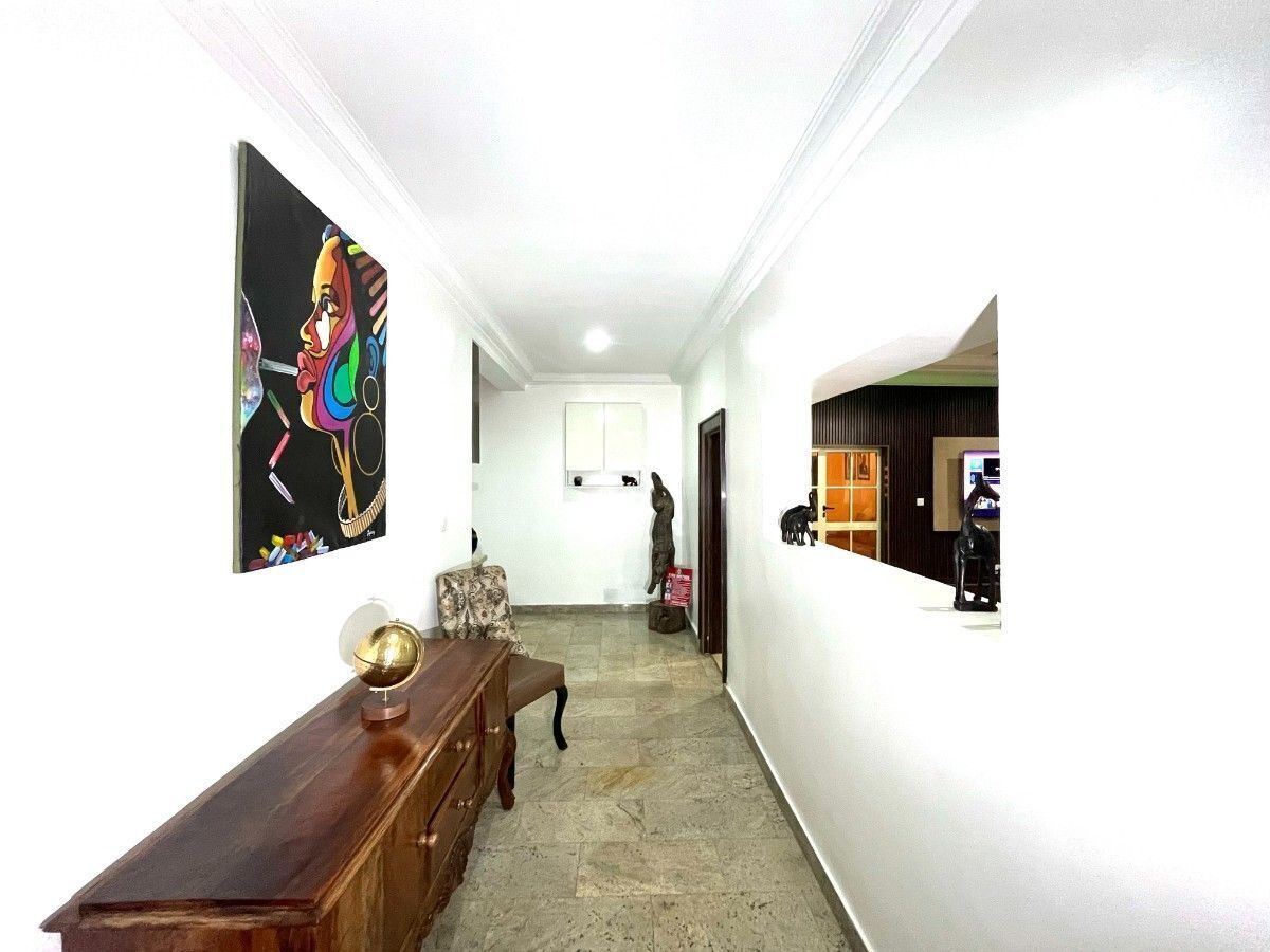 A hallway with a wooden bench, a globe, and a painting on the wall.