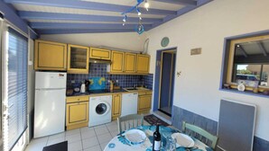 Cocina compacta con armarios amarillos, lavadora y comedor con una mesa dispuesta para dos personas.