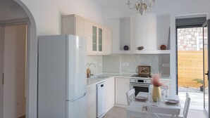 Cozinha moderna com armários brancos, forno embutido e área de refeições com mesa e cadeiras.