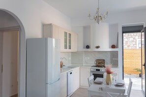 A modern kitchen with white cabinetry, a built-in oven, and a dining area with a table and chairs. - Villa Iliousa Prinsess Peaceful Getaway in Rhodes for families & couples (RHODES)