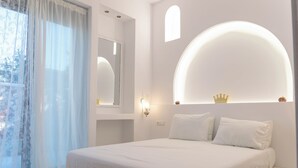 Quarto com cama, espelho, luminária na parede e janela com cortinas.
