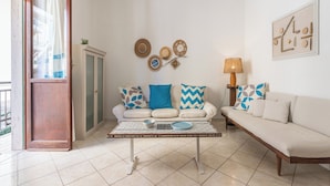 A living room with a sofa, a coffee table, and a lamp. There is a door leading to an outdoor area. - First-floor Apartment Just Steps From the sea (Alghero)