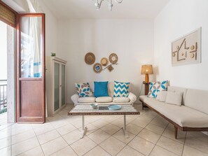 A living room with a sofa, a coffee table, and a lamp. There is a door leading to an outdoor area. - First-floor Apartment Just Steps From the sea (Alghero)