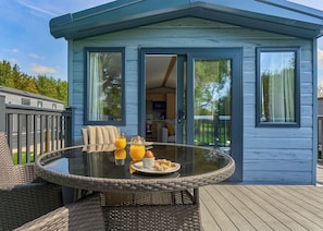 A dining area with a glass table, wicker chairs, and a breakfast setting with orange juice and eggs. - Luxury Holiday Home 3 bed (Hayle)