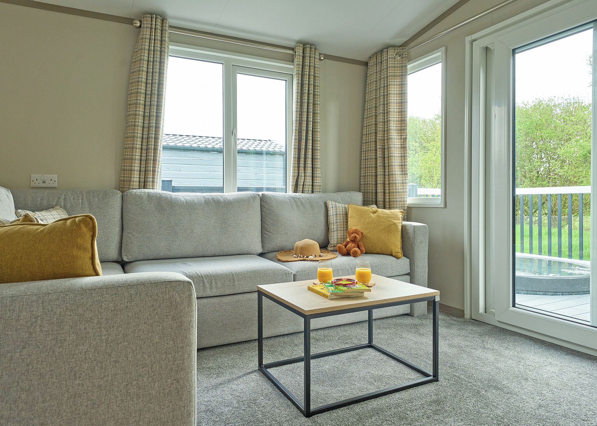 A living room with a grey sofa, a coffee table, and a view of a balcony.
